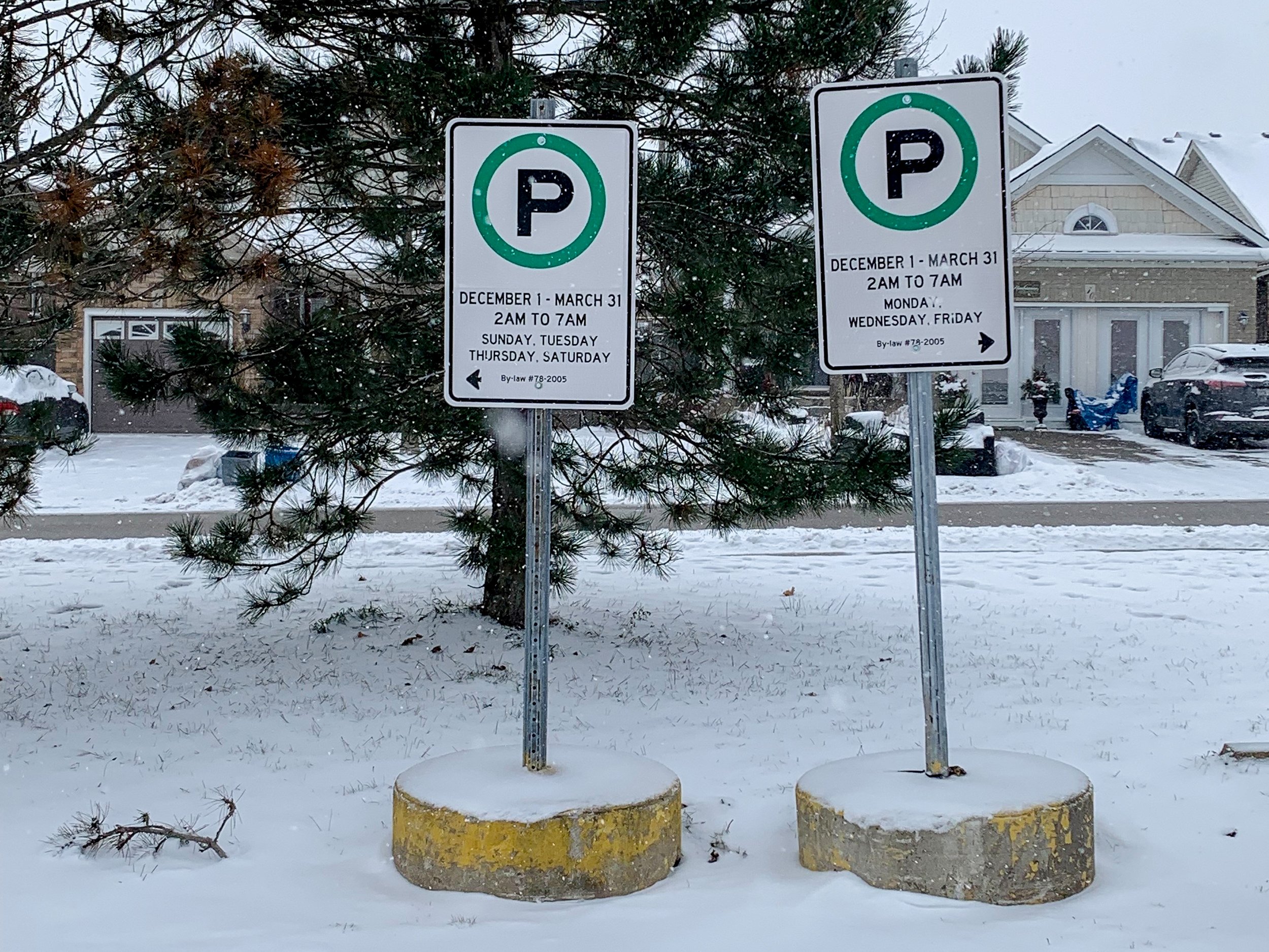 Two winter parking bylaw signs in a Town overnight parking lot.